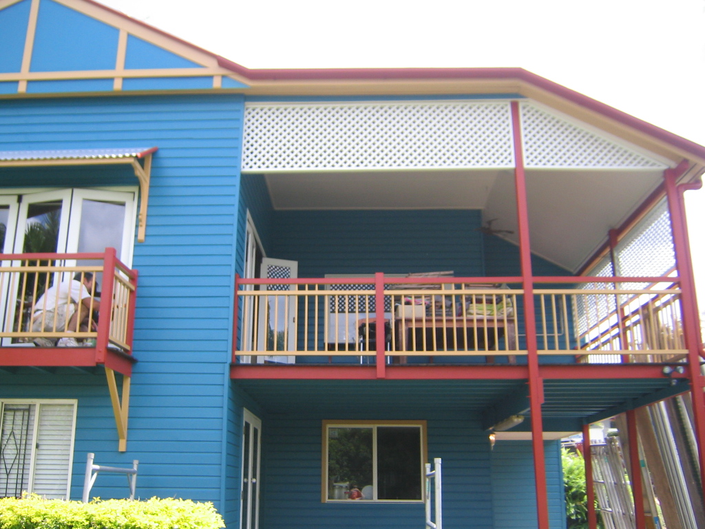 Blue weatherboard Queenslander with red and cream painted trim