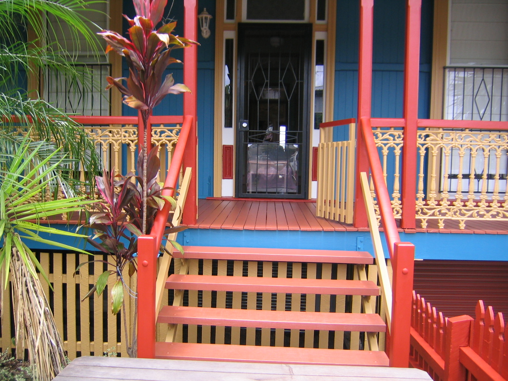 Queenslander verandah, steps and fretwork painted in red, cream and blue
