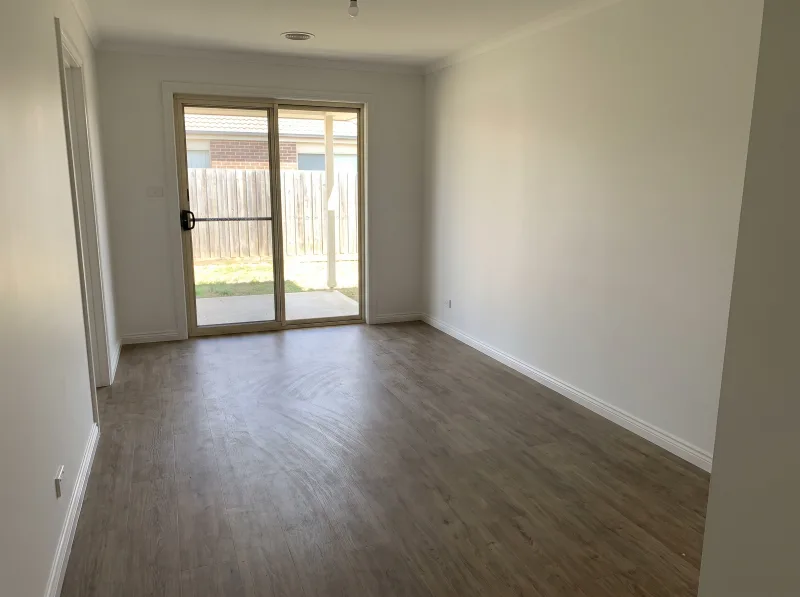 An empty rental living room with freshly touched-up white walls and clean skirting boards